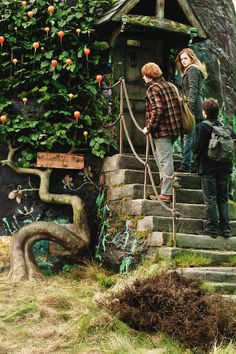 two people are standing on the steps to a small house with plants growing out of it