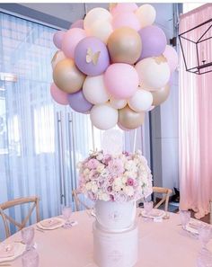 a bunch of balloons that are on top of a table with some flowers in it