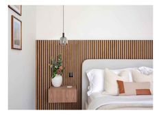 a bed with white sheets and pillows next to a wooden headboard on the wall