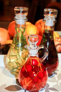 two glass vases filled with red berries on top of a white table next to oranges and lemons