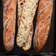 three loaves of bread sitting on top of a black tray next to each other