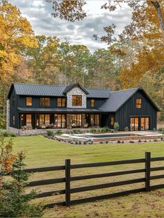 a large black house in the middle of a field with trees and grass around it