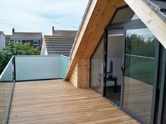 a wooden deck with sliding glass doors leading up to the top floor and roof area