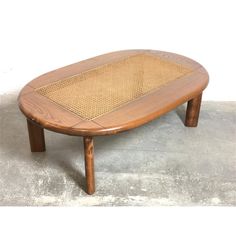 a wooden coffee table with wicker on the top and bottom, against a white background