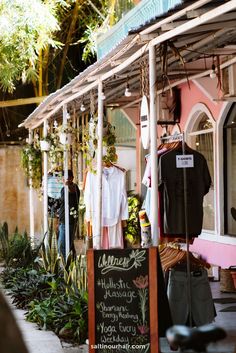 an outdoor market with clothes and plants on display