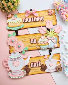 some wooden signs that are on top of a pink and white tablecloth with candy