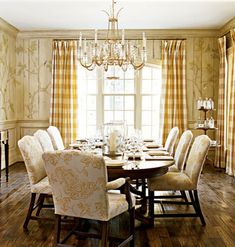 a dining room table with chairs and a chandelier in front of a window