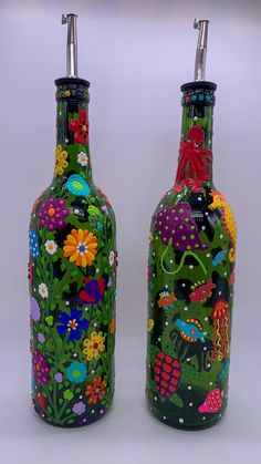 two colorful vases are sitting side by side on a white surface, one is decorated with flowers and birds