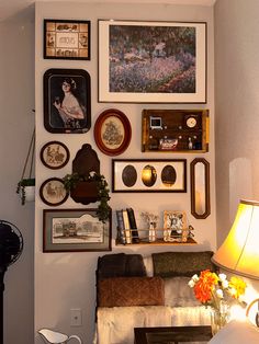 a living room filled with lots of framed pictures on the wall above a couch and table