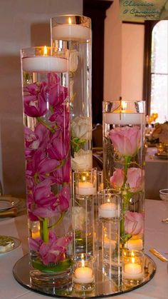 flowers and candles are arranged in glass vases