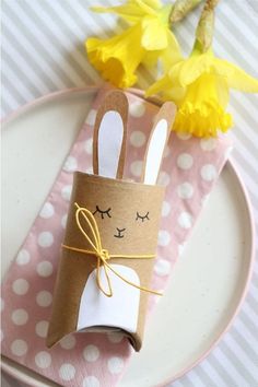 a paper roll with a bunny on it sitting on a plate next to yellow flowers