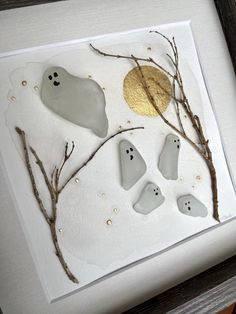 some white rocks and branches with gold leaf on them in a shadow box, next to a framed photograph