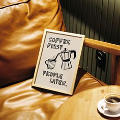 a sign that says coffee first, people later on a table next to a chair