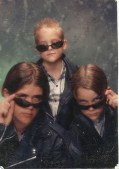 three children with sunglasses on their faces are posing for a photo in front of the camera