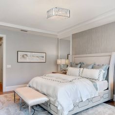 a large white bed sitting in a bedroom next to a doorway with a chandelier