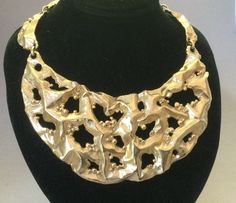 "Beautiful impressed dimensional pierced open work melted metal choker/collar bib necklace. Very popular in the '70s. Possibly made in 1972. Lies nicely at the collar bone. Single articulated segmented bib necklace designed by Eugene Bertolli with scallops dancing along to the chain clasp.. Bertolli; without a doubt, a master craftsman. Adjustable. Shows no wear; near new condition. Please look carefully. ( one tiny series of spots on one link) See Photo #7. Signed Napier in block letters on the Melted Metal, Melting Metal, Metal Choker, Block Letters, Book Pieces, Collar Bone, Bib Necklaces, Bone Beads, Choker Collar