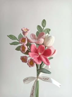 a bouquet of crocheted flowers in a vase with a ribbon tied around it