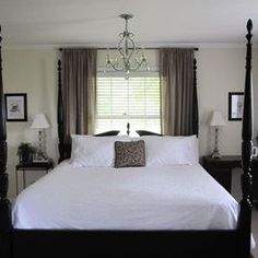 a white bed sitting in a bedroom next to a window