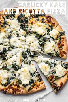 a pizza with cheese, spinach and other toppings cut into eight slices on top of white paper