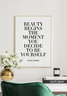 a green chair in front of a white wall with a framed quote on it that says beauty begins the moment you decide to be yourself