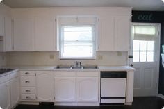 an empty kitchen with white cabinets and black counter tops, including a dishwasher