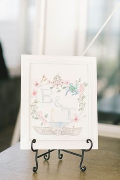 a white framed sign sitting on top of a wooden table