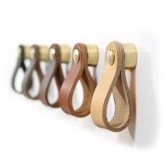 four leather handles hang on a white wall