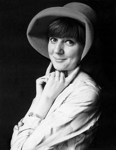 a black and white photo of a woman wearing a hat with her hand on her chin