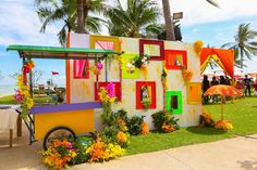 an ice cream cart decorated with flowers and umbrellas on the grass near palm trees