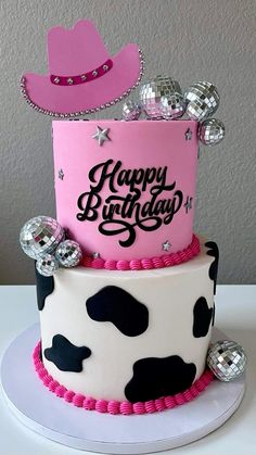 a birthday cake decorated with cow print and pink frosting is sitting on a table