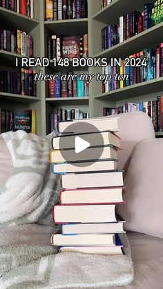 a pile of books sitting on top of a bed in front of a book shelf