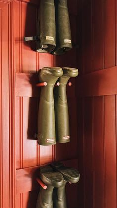 three green boots are hanging on the wall next to each other in a red room