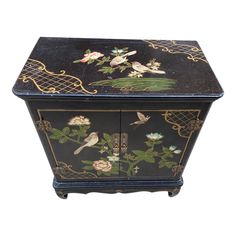 a black and gold painted cabinet with flowers on it