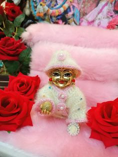 a small doll sitting on top of a table next to red roses and other decorations