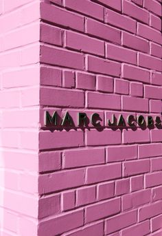 the word marc jacobs is spelled in black on a pink bricked wall