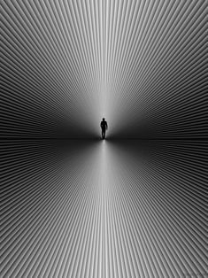 a black and white photo of a person standing in the middle of an abstract tunnel