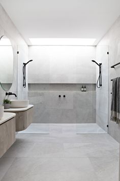 a white bathroom with two sinks, mirrors and a large shower stall in the corner