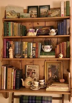 an old wooden shelf with books and tea cups on it, along with other antique items