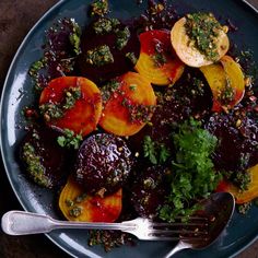 a plate with beets, carrots and parsley on it next to a fork