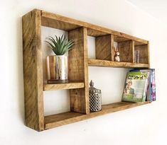 a wooden shelf with some books and vases on top of it next to a white wall