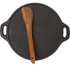 a black cast iron skillet with a wooden spoon on it's side, isolated against a white background