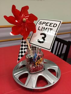 a red table topped with a jar filled with candy and a sign that says speed limit