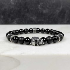 Complement your rock and roll style with our sinister skull stretch bracelet. Our signature skull bead is the center attraction on this bracelet. This bracelet is bold enough to stand on its own, but for a more dramatic look, stack it with the coordinating gemstone bracelets. Or mix and match with our other gemstone bracelets to complete your own unique rockstar look. The large skull bead has a flat back, which allows the skull to fit flat against your wrist. Made with pewter and gemstone beads Rockstar Look, Rock And Roll Style, Embrace Your Dark Side, The Sinister, Rock N Roll Style, Skull Bracelet, Beaded Skull, Onyx Gemstone, Lava Rock