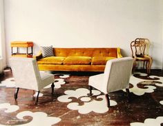 a living room with two chairs and a couch in front of a large wall mural