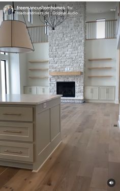 an empty living room with wood floors and white brick fireplace in the center, surrounded by built - in shelving