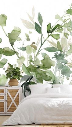 a white bed sitting next to a green plant wall mural on the side of a bedroom