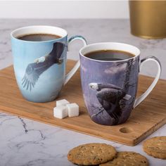 two coffee mugs on a tray with cookies