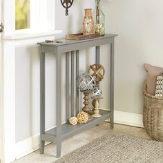 a small console table with some decorative items on it and a basket next to it