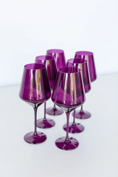 six purple wine glasses sitting on top of each other