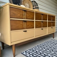 an old dresser with many drawers and baskets on it's top, next to a rug in front of a house